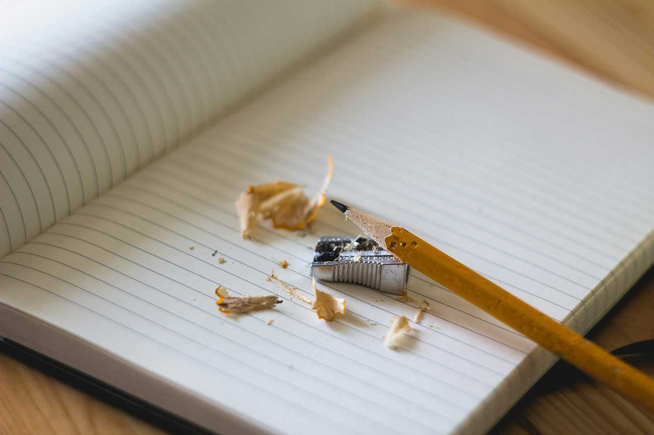 Close up shot of a pencil near a pencil sharpener on an open notebook