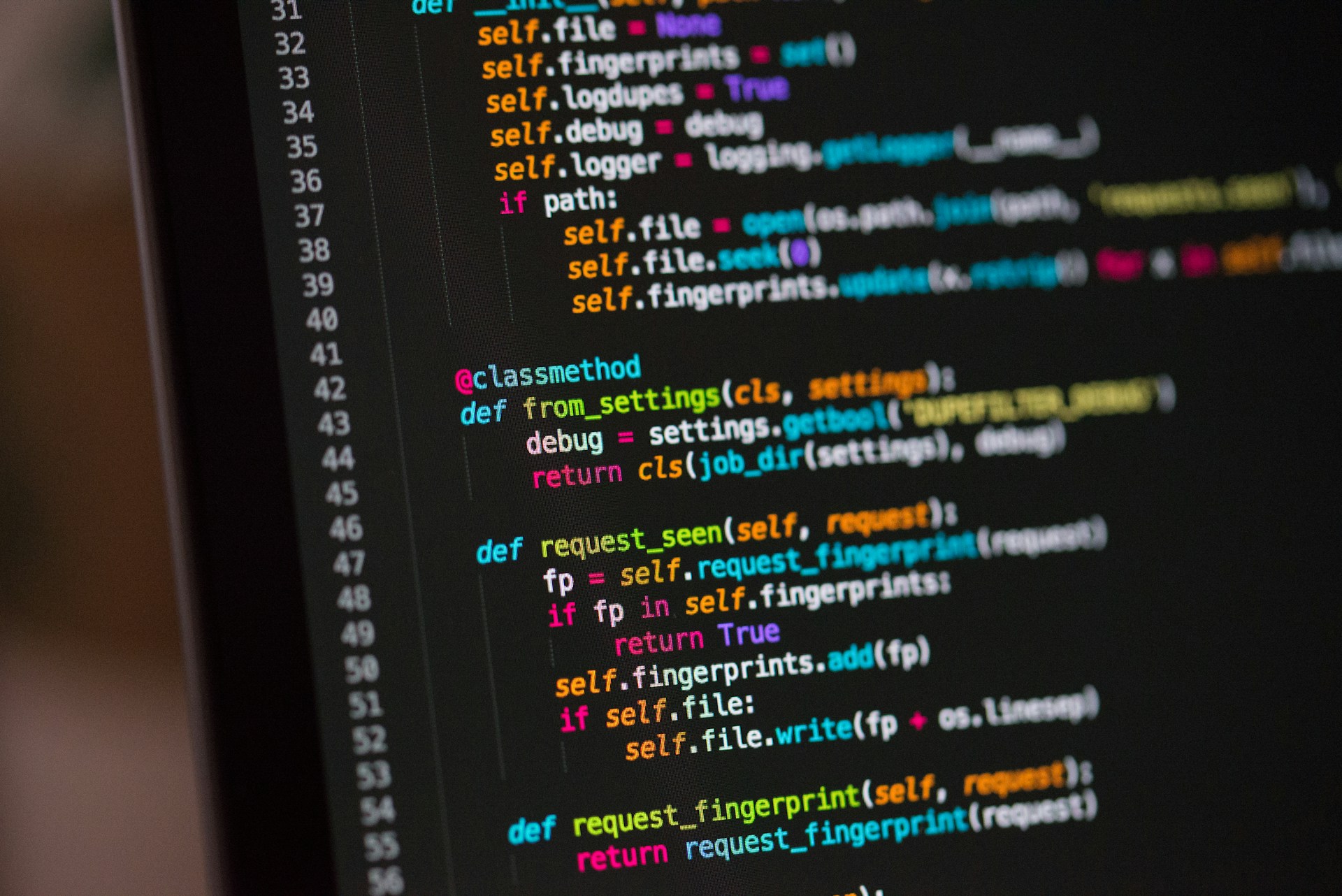 Programing code on a laptop monitor. The background is blurred.